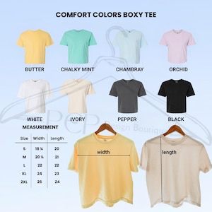 May include: A display of Comfort Colors Boxy Tees in various colors, including Butter, Chalky Mint, Chambray, and Orchid. The image also shows White, Ivory, Pepper, and Black tees. Measurements are provided for sizes S to 2XL, with widths ranging from 18 3/4 inches to 26 inches and lengths from 20 inches to 24 inches.