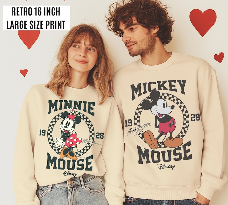 Może przedstawiać: Kremowe bluzy z nadrukami Myszki Miki i Myszki Minnie. Bluzy mają czarny tekst i grafikę, w tym słowa "Mickey Mouse" i "Minnie Mouse". U g&oacute;ry znajduje się tekst "Retro 40.6 cm duży nadruk".