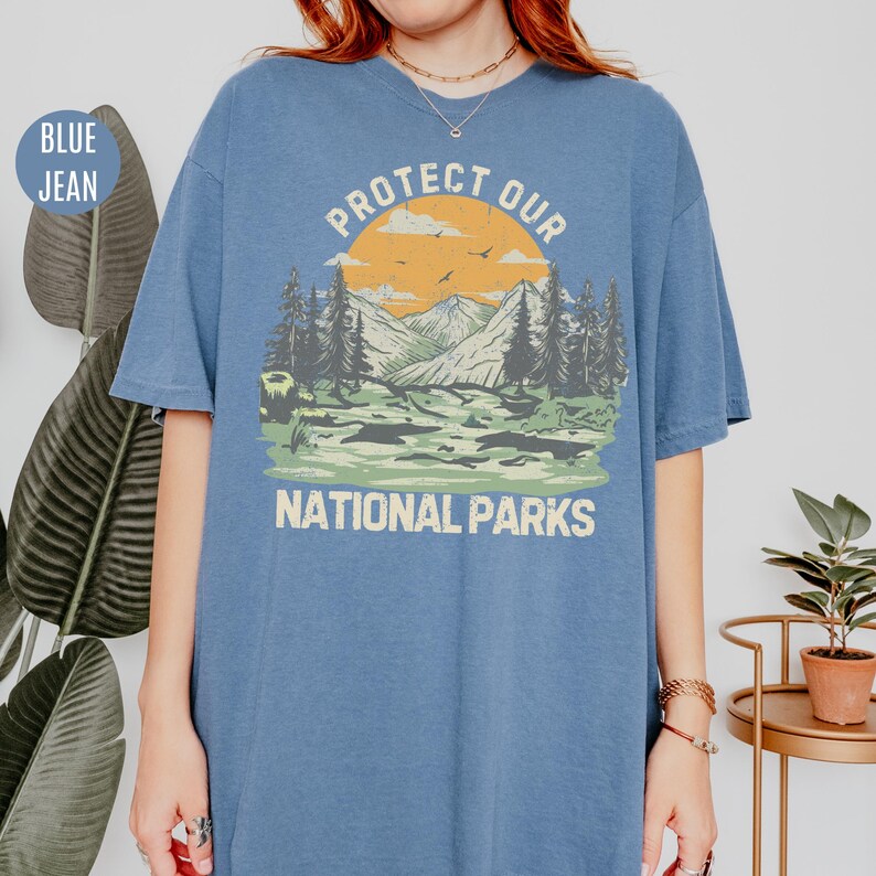 May include: A blue jean t-shirt with a graphic of a mountain landscape and the text "Protect Our National Parks".