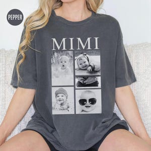 May include: A dark gray t-shirt with the word "MIMI" printed in white on the front. The shirt features a collage of four black and white photos of babies.