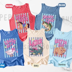 K&ouml;nnte beinhalten: Eine Auswahl von sechs Tanktops in verschiedenen Farben, darunter Rot, Blau und Elfenbein. Jedes Tanktop hat ein einzigartiges Grafikdesign mit Text und Illustrationen von Tieren wie Pferd, Fisch, Alligator, Gans und Bison.
