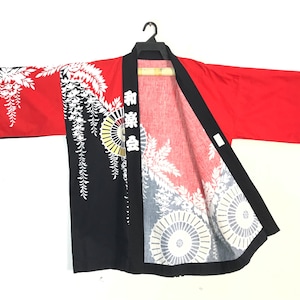 May include: Red, black, and white Japanese kimono-style jacket. The jacket features a red body with black sleeves and a black front panel. White floral and circular designs adorn the sleeves and front panel. The text "和楽会" is printed vertically on the front.