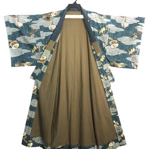 May include: A teal kimono featuring a repeating pattern of white clouds, lanterns, and small drums. The garment has wide sleeves, a solid dark blue collar, and a plain brown interior lining. The robe is displayed on a black plastic hanger.
