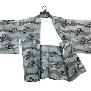 May include: A gray kimono with a cloud and mountain pattern. The kimono is hanging on a black hanger against a white background. The pattern features black and gray cloud and mountain designs.