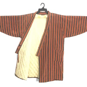 May include: A striped, open-front robe with a quilted cream-colored lining. The robe features vertical stripes in shades of orange and black. It has two pockets and is hanging on a black hanger.