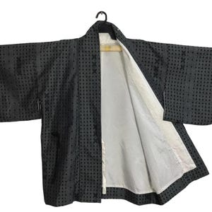Puede incluir: Un kimono negro con forro blanco y un patrón de lunares. El kimono está abierto y el forro es visible.