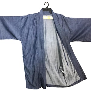 May include: A blue denim kimono-style robe hangs from a black hanger. The robe is open, revealing a lighter-colored interior. The sleeves are wide and the fabric appears lightweight. The garment is a solid blue color.