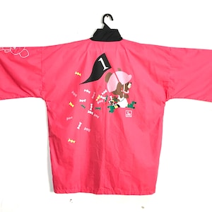 May include: A vibrant pink kimono jacket with a black collar and short sleeves. The back displays a cartoon bear in a pink hat, holding a flag with the number 1. Multi-coloured confetti shapes are scattered around the bear.