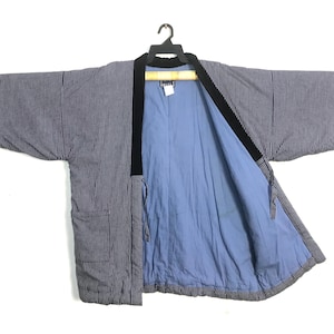 May include: A navy and white striped kimono jacket with a black collar and light blue lining. The jacket is hanging on a black hanger against a white background.