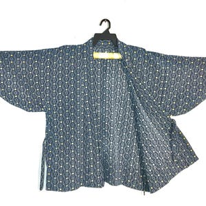 May include: A dark blue haori jacket featuring a repeating white and yellow geometric pattern of interconnected circles. The garment has wide, loose sleeves, an open front design, and is displayed on a black plastic hanger against a white background.