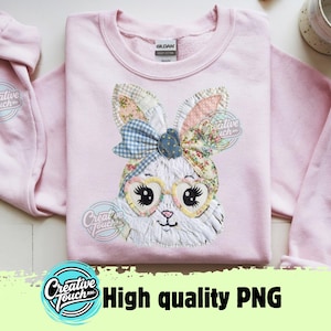 Peut inclure: Un sweat-shirt rose clair avec un motif de lapin en patchwork. Le lapin porte des lunettes et un nœud bleu. Les oreilles sont à motifs floraux et vichy. Le texte "Creative Touch" est sur la manche et "High quality PNG" en bas.