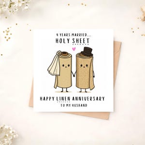 May include: A square greeting card featuring two cartoon linen rolls holding hands. The left roll wears a white veil, and the right roll wears a black top hat. Text reads: 4 YEARS MARRIED... HOLY SHEET. HAPPY LINEN ANNIVERSARY TO MY HUSBAND.