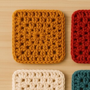 May include: Close-up of several crocheted squares in various colors. The squares are in shades of mustard yellow, red-orange, cream, and teal. Each square features a floral pattern and a textured appearance, suggesting handmade craftsmanship.