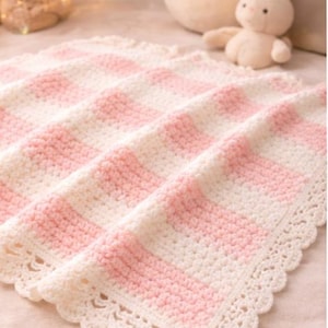 May include: A handmade, soft, pink and white striped crochet baby blanket. The blanket has a scalloped edge and is made of a soft yarn. The blanket is a cozy and decorative item for a nursery or baby's room.