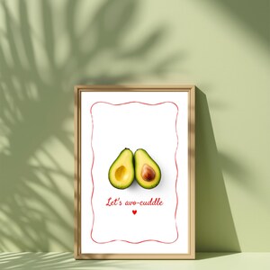 Könnte beinhalten: Ein gerahmter Druck mit zwei Avocadohälften und dem Text "Let's avo-cuddle" in Rot. Die Avocados sind grün mit gelbem Fruchtfleisch und einem braunen Kern. Der Druck hat einen roten Rahmen und einen Holzrahmen.