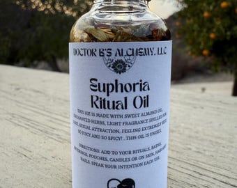 Puede incluir: Una pequeña botella de vidrio con una etiqueta blanca que dice "DOCTOR B'S ALCHEMY. LLC" y "Euphoria Ritual Oil". La etiqueta también incluye instrucciones de uso y un corazón con una cara dentro. La botella está llena de un líquido transparente y tiene una tapa negra.