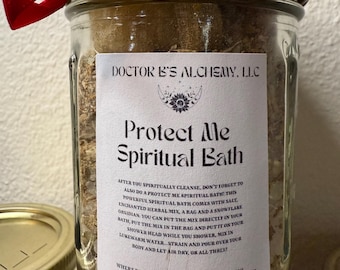 May include: A glass jar with a red ribbon tied around the lid. The jar contains a white, crystal-like substance and herbs. The label on the jar reads "Protect Me Spiritual Bath" and includes the text "DOCTOR B'S ALCHEMY. LLC - SAN DIEGO, CA".