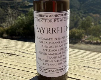 Peut inclure: Une bouteille en verre d'encre de myrrhe avec un bouchon noir, étiquetée "Doctor B's Alchemy". L'étiquette contient du texte sur l'encre faite à la main pour les talismans et la magie. La bouteille est sur une surface en bois avec un arrière-plan de montagne.