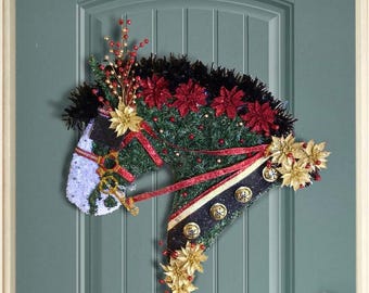 May include: A Christmas wreath shaped like a horse's head, decorated with red and gold poinsettias, green garland, and black and gold ribbon.