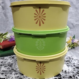 Könnte beinhalten: Ein Satz von drei Vintage-Aufbewahrungsbehältern mit Deckeln. Die Behälter sind gelb und grün mit braunen geometrischen Mustern. Die Behälter sind übereinander gestapelt.