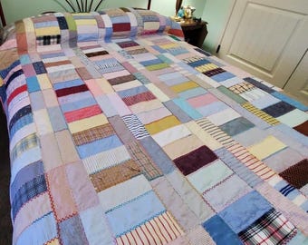 Könnte beinhalten: Eine Patchwork-Decke in Pastelltönen wie Blau, Rosa, Gelb und Weiß bedeckt ein Bett. Die Decke besteht aus rechteckigen Stoffstücken, die zusammengenäht sind. Das Bett hat ein dekoratives Metallkopfteil.