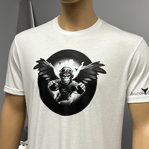 May include: White t-shirt with a black and white graphic of a monkey wearing a pilot's helmet and goggles, with wings, flying in a circle. The text "AVIATION ART.COM" is on the right sleeve.
