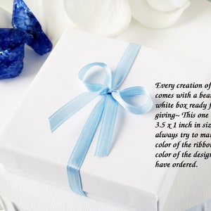 May include: A white gift box with a light blue ribbon tied in a bow. The box is 3.5 x 3.5 x 1 inches in size. The text on the box reads: "Every creation of mine comes with a beautiful white box ready for gift giving~ This one is 3.5 x 3.5 x 1 inch in size. I always try to match the color of the ribbon to the color of the design you have ordered."