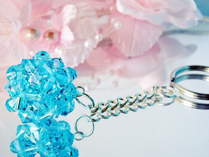 May include: A turquoise blue crystal charm attached to a silver chain with a silver key ring.