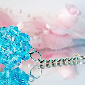 May include: A light blue crystal keychain with a silver chain. The crystal is shaped like a ball and is made up of many small, faceted pieces.
