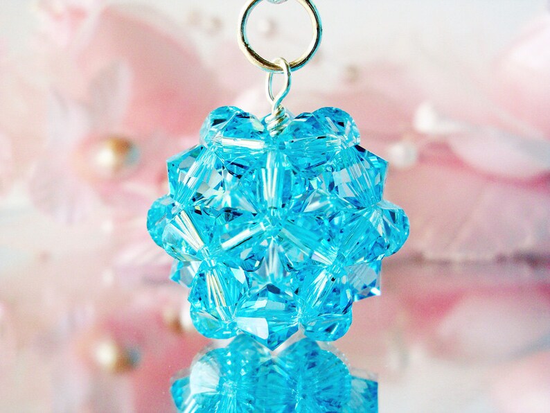 May include: A silver pendant with a cluster of light blue crystal beads in a geometric shape.