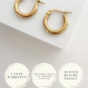 May include: A pair of gold-colored hoop earrings. The earrings have a classic, rounded design and a polished finish. The image is set against a white background. The earrings are a timeless jewelry accessory.
