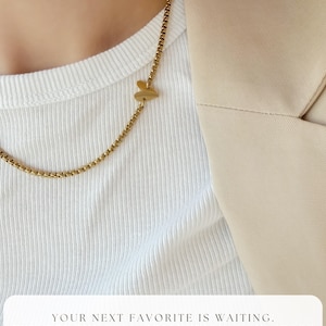 May include: A gold-toned box chain necklace featuring a small, smooth heart-shaped charm. The text at the bottom reads: YOUR NEXT FAVORITE IS WAITING. EXPLORE THE FULL COLLECTION IN MY STORE. FOLLOW LINK IN DESCRIPTION.