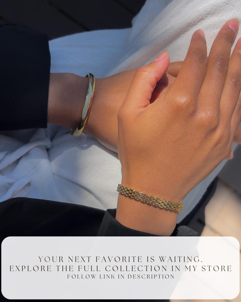 May include: A close-up of two wrists adorned with gold bracelets. One is a solid, polished bangle, and the other is a chain-link style. The image includes the text: "YOUR NEXT FAVORITE IS WAITING. EXPLORE THE FULL COLLECTION IN MY STORE FOLLOW LINK IN DESCRIPTION."