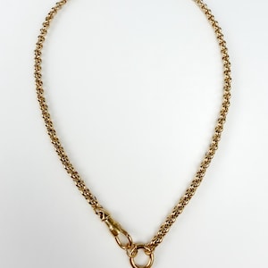 May include: A gold-toned chain necklace featuring a series of interlocking circular links. The necklace includes a swivel lobster clasp mechanism attached to a circular ring, allowing for a secure closure and a classic, uniform link design.