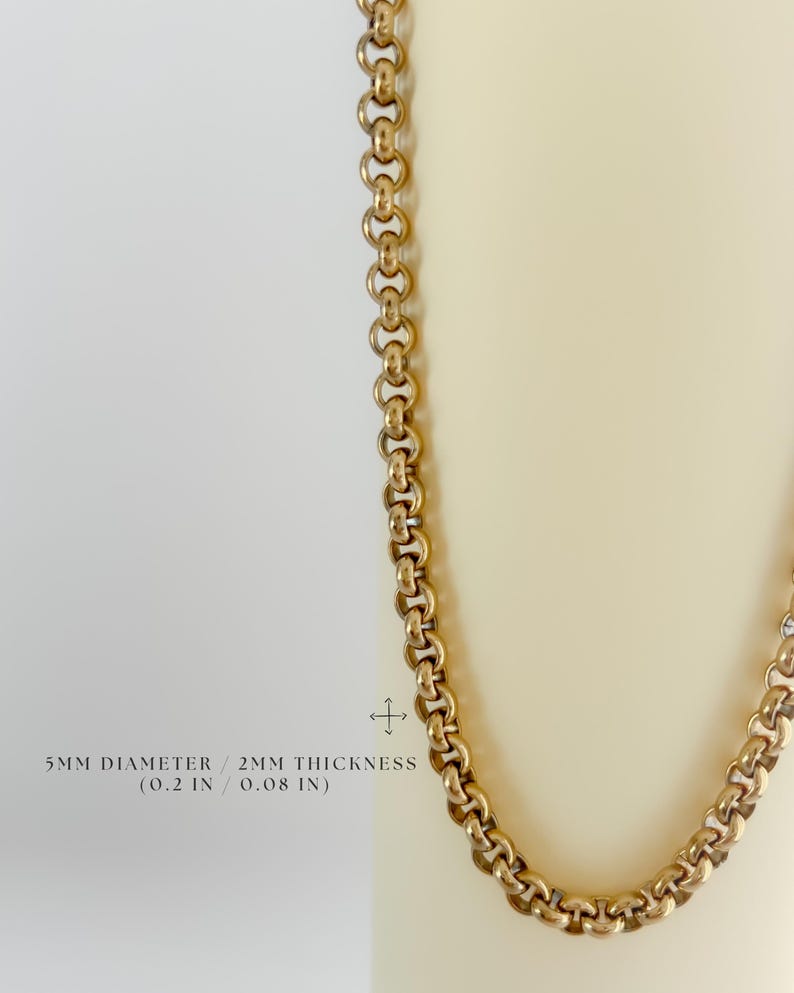 May include: A gold-toned rolo chain necklace featuring round interlocking links. The text on the image indicates a 5mm diameter and 2mm thickness, which corresponds to 0.2 inches and 0.08 inches respectively. The chain has a polished finish.