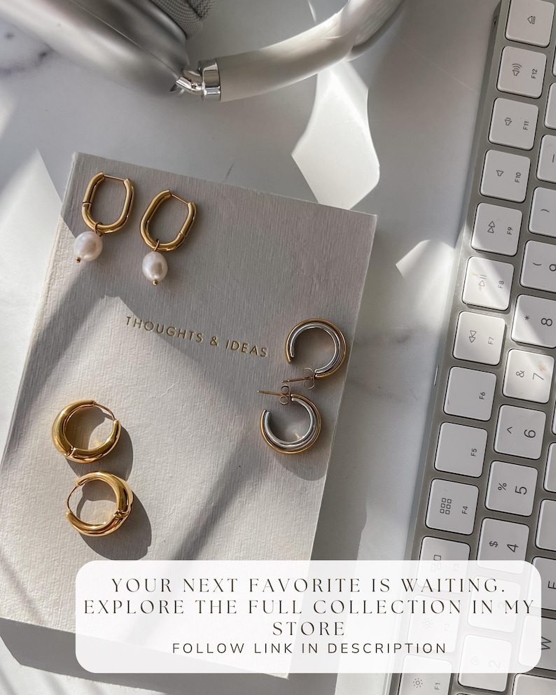 Flat lay of multiple NONO SF hoop earrings on neutral surface near a keyboard. Everyday gold earring styles built for mixing and matching.