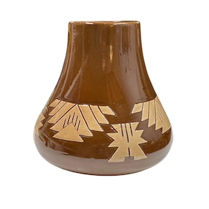 May include: A brown ceramic vase with a wide base and a narrower top. The vase features a band of beige geometric designs around the lower portion. The vase has a glossy finish and is likely handmade.