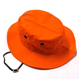 May include: A bright orange hunting hat with a wide brim and a black drawstring. The hat has two small black eyelets on the crown.