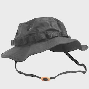 May include: A black boonie hat with a wide brim and a chin strap. The hat features a fabric band around the crown and eyelets for ventilation. The chin strap has an adjustable toggle. This hat is designed for outdoor activities.