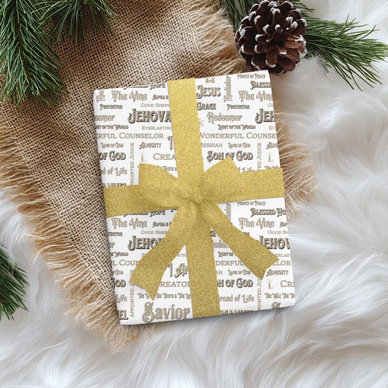 May include: A wrapped gift with white paper printed with religious words like "Jehova" and "Jesus" in a repeating pattern. The gift is tied with a gold glitter ribbon and bow. The background includes a pine cone and greenery.