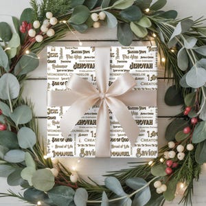 May include: A wrapped gift with a cream-colored bow, surrounded by a festive wreath of greenery and berries. The gift wrap features religious text in black and gold lettering, including the words "Jesus" and "Jehovah".