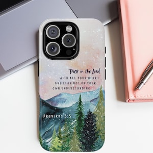 May include: A phone case with a watercolor design of a snowy mountain range and a forest. The case features the text "Trust in the Lord with all your heart and lean not on your own understanding" and "Proverbs 3:5".