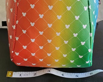 May include: A small rainbow-colored backpack with a white Mickey Mouse pattern. The backpack has a black zipper and a black strap.