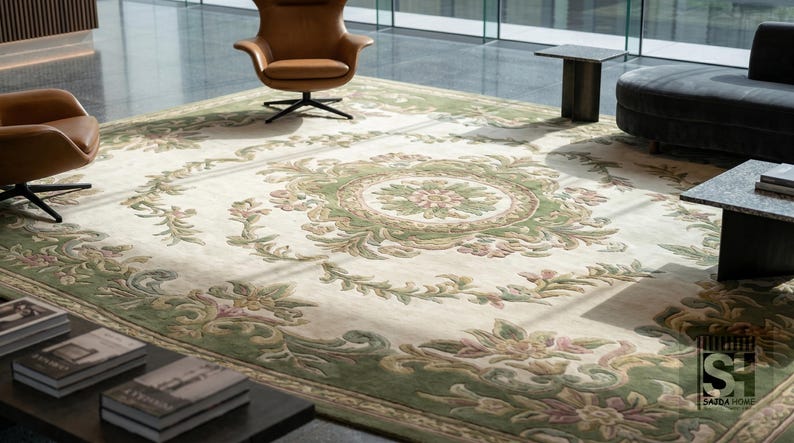 Puede incluir: Gran alfombra rectangular con fondo crema y un detallado dise&ntilde;o floral en tonos verdes y rosas. La alfombra presenta un dise&ntilde;o de medall&oacute;n central y un borde decorativo. Se encuentra en un espacio de vida moderno con sillones de cuero y un sof&aacute; oscuro. Mide aprox. 300 x 400 cm.