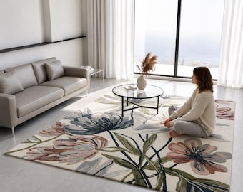 May include: A rectangular area rug featuring a cream-colored background with large, stylized floral patterns in shades of muted blue, dusty pink, and olive green. The design includes long, sweeping stems and leaves that extend across the surface.