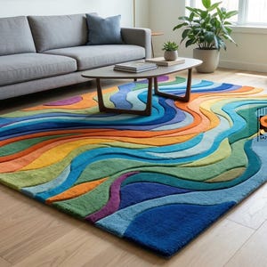May include: A multi-coloured rug with an abstract, flowing design. The rug displays a vibrant mix of blues, greens, oranges, yellows, and purples, forming a wave-like pattern. It's in a living room with a grey sofa and wooden flooring.