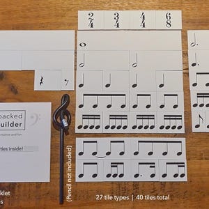 May include: A set of 40 white rhythm tiles with black musical notes and symbols. The tiles are arranged in rows on a wooden surface. The tiles are labelled with numbers and include a booklet titled "Music Unpacked Rhythm Builder".