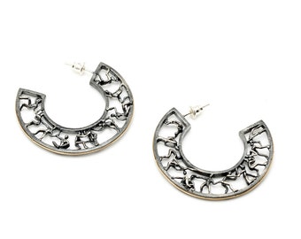 May include: A pair of silver hoop earrings with a delicate, intricate design. The earrings are made of metal and have a gold-toned edge.