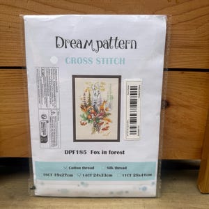 May include: A cross-stitch kit featuring a forest scene with foxes, titled "Fox in forest." The kit includes cotton thread and comes in three sizes: 19x27cm, 24x33cm, and 28x41cm. The packaging displays the "Dream pattern" logo.