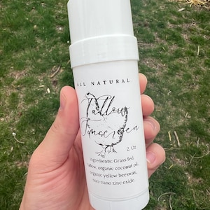 May include: White deodorant stick with a black label that says "ALL NATURAL" and "Tallow  Tinocren" with a chicken illustration. The label also lists the ingredients: "Grass fed tallow, organic coconut oil, organic yellow beeswax, non-nano zinc oxide" and the size: "2.0z".